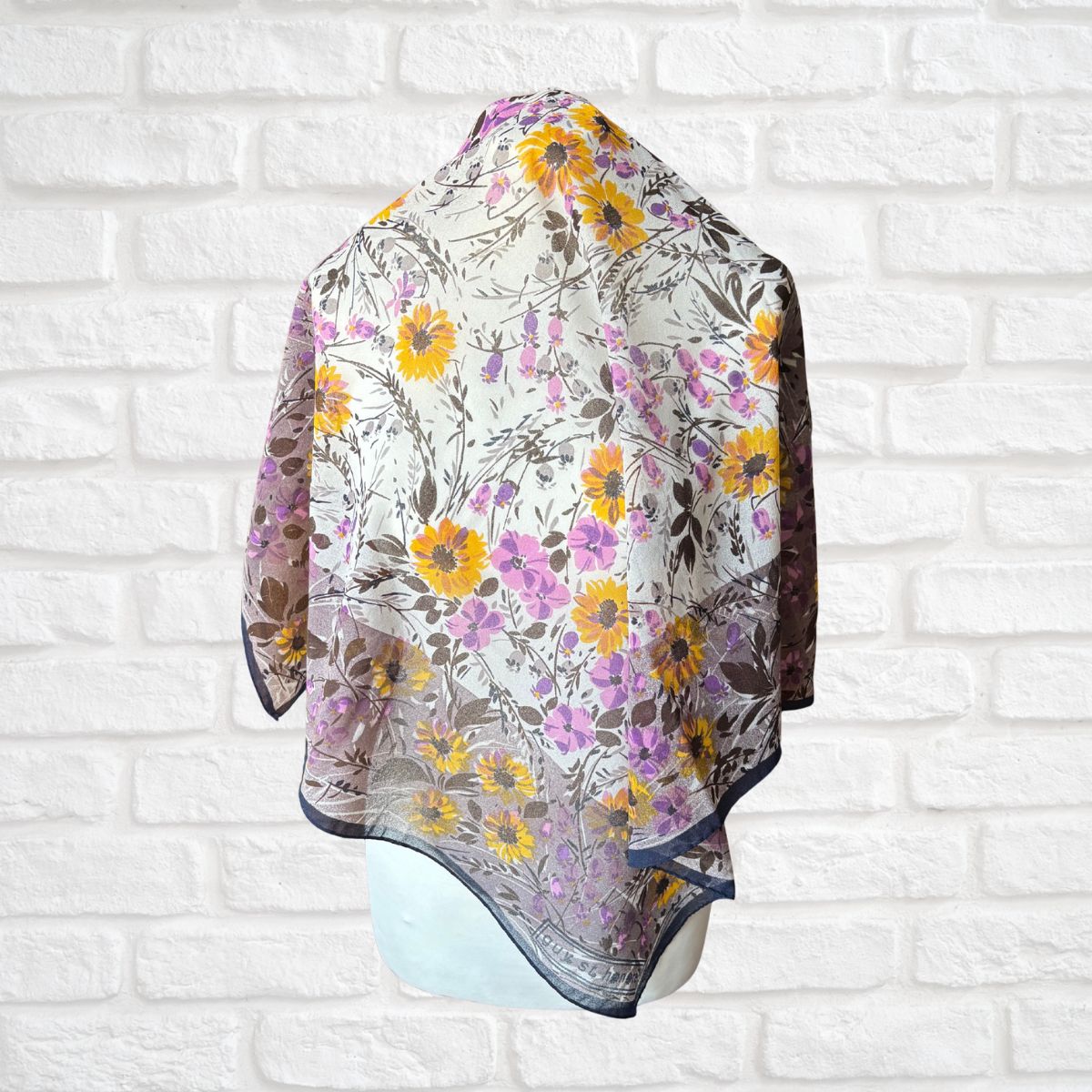 Floral patterned scarf draped over a white brick wall