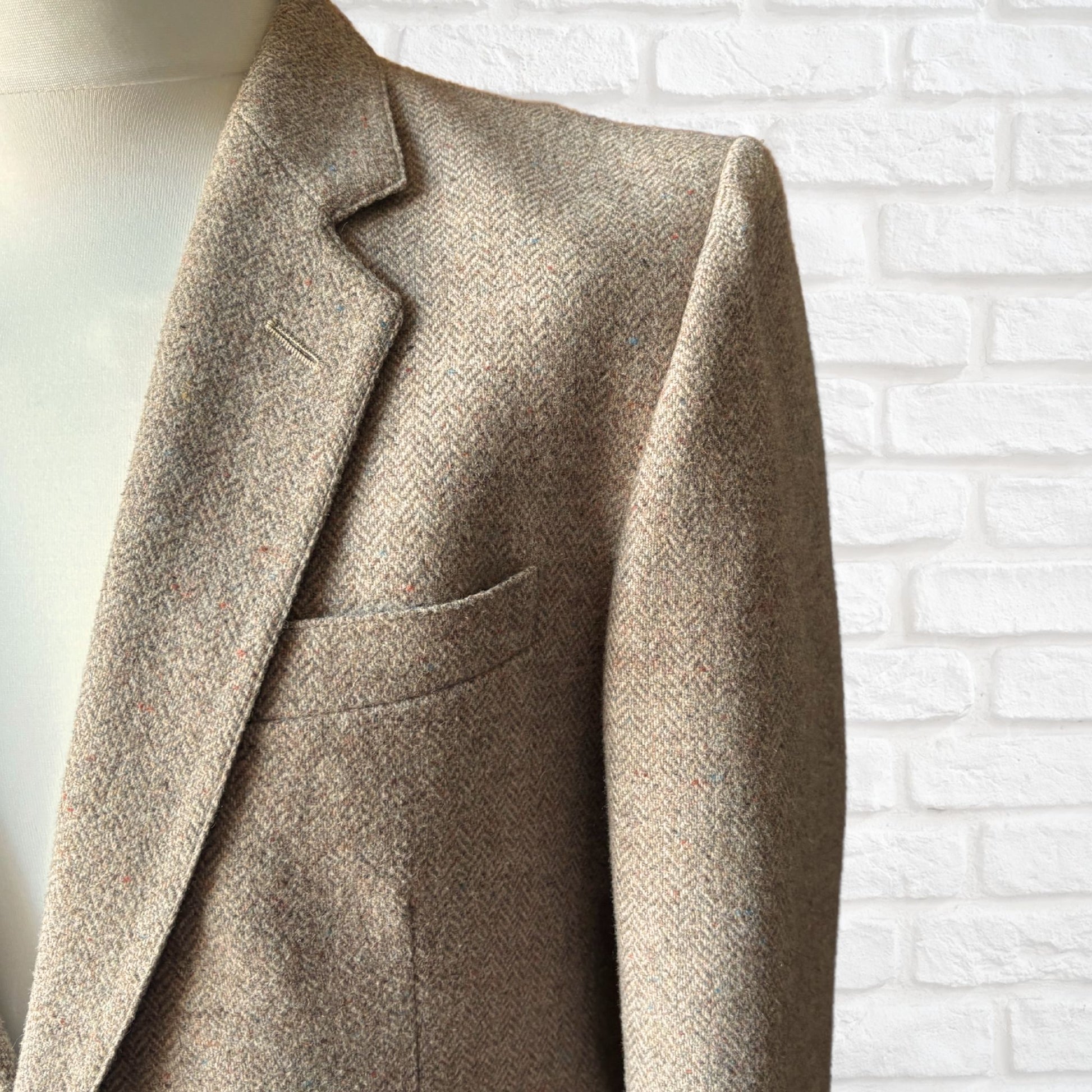 Beige blazer on a mannequin against a white brick wall.