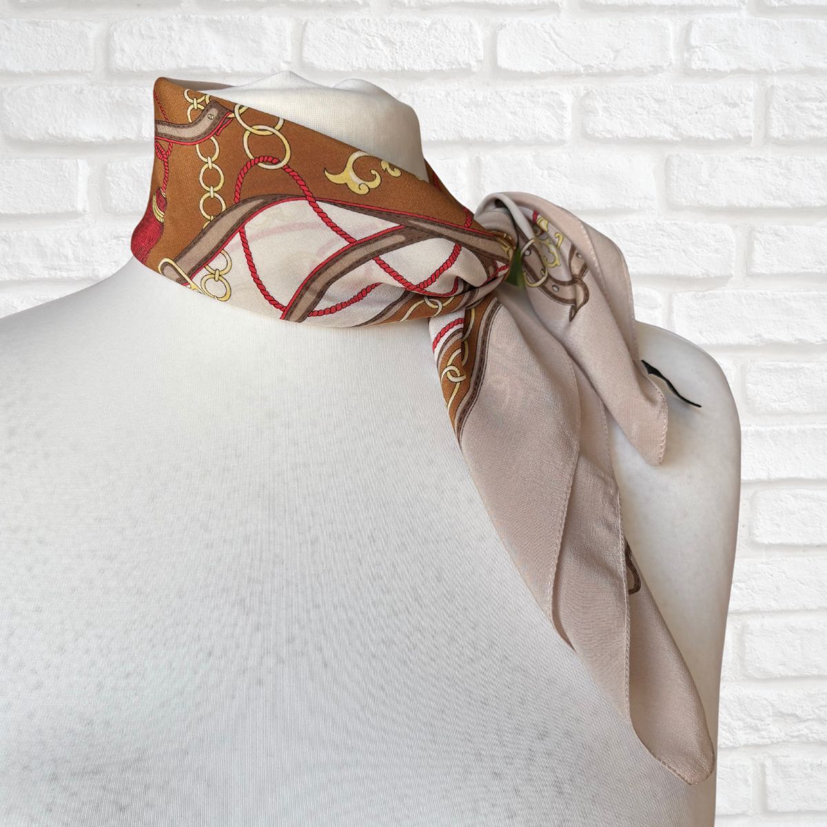 Mannequin wearing a patterned scarf against a white brick wall background