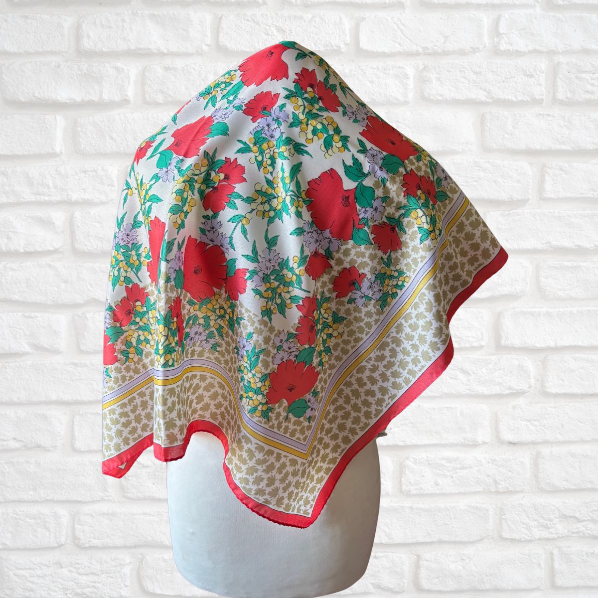 Floral patterned scarf on a mannequin against a white brick wall background