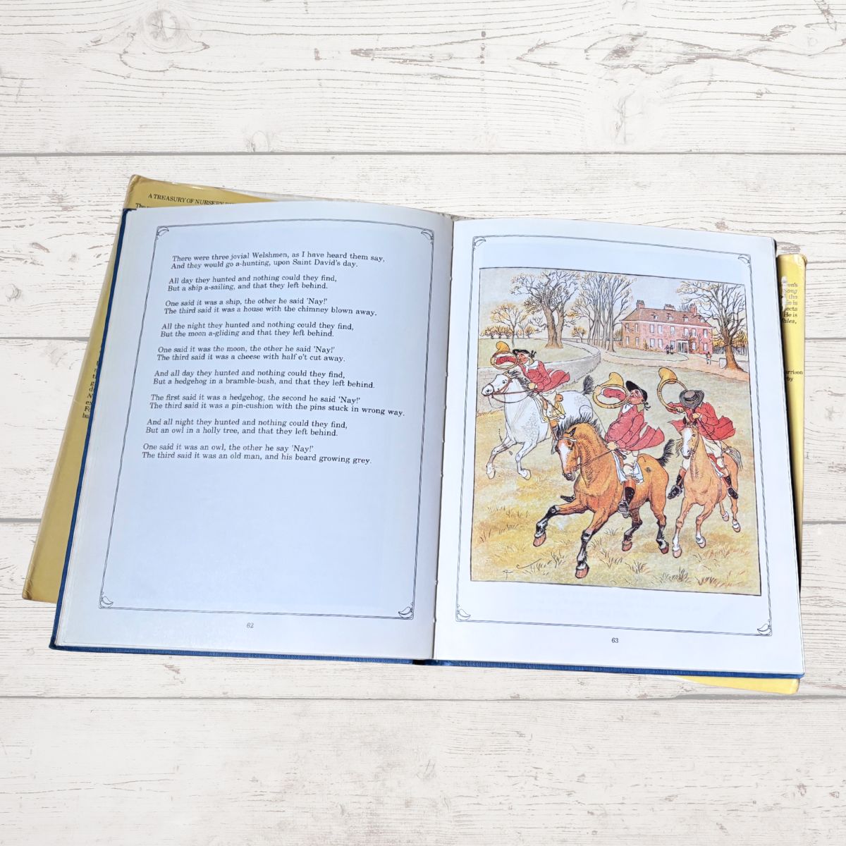An open children's book lying flat on a light wood surface, showing printed text on the left page and a colorful illustration of horse riders on the right page.