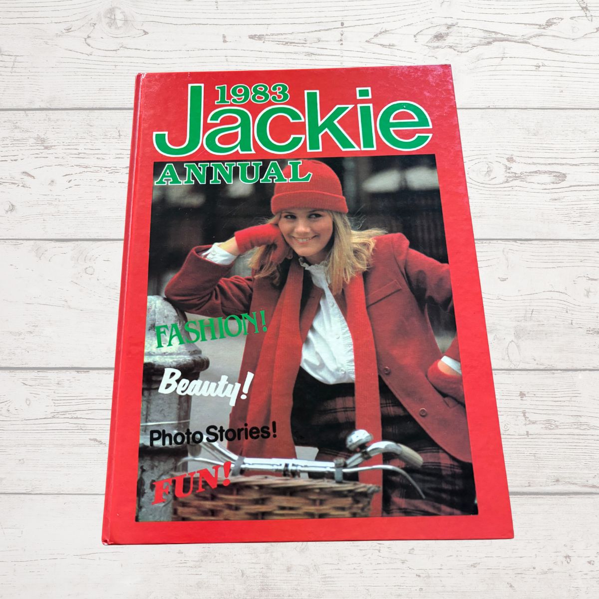 1983 Jackie Annual book cover with a woman in a red coat and hat on a light wooden surface