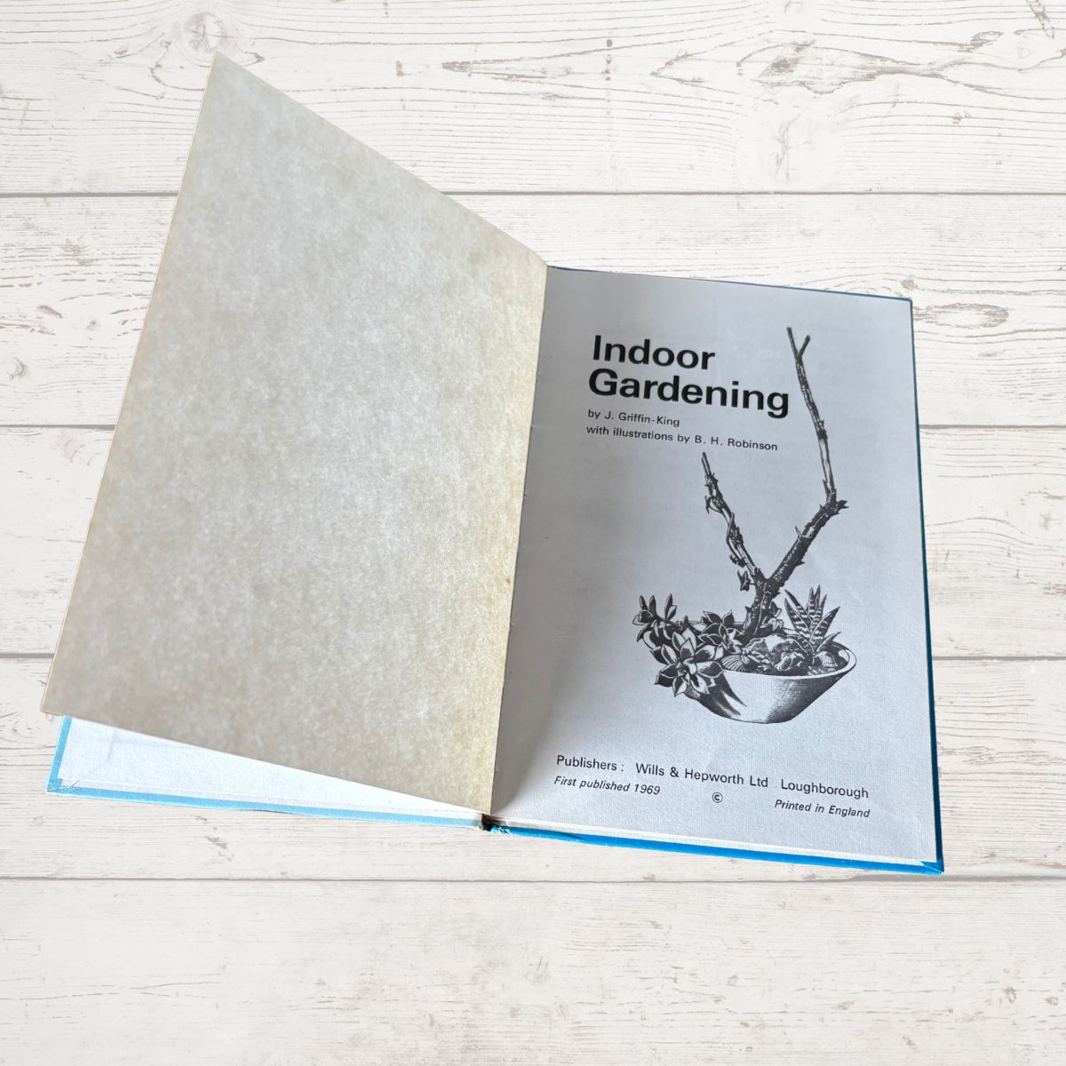 Open book with an indoor gardening guide on a wooden surface