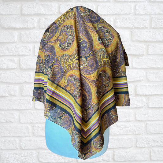 Patterned scarf draped over a mannequin  against a white brick wall