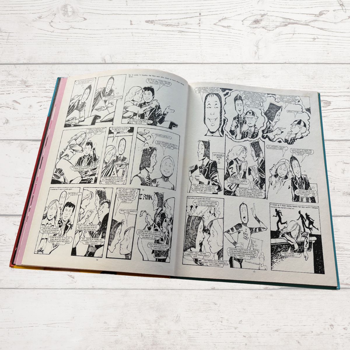 Open book with comic strip on a light wooden surface