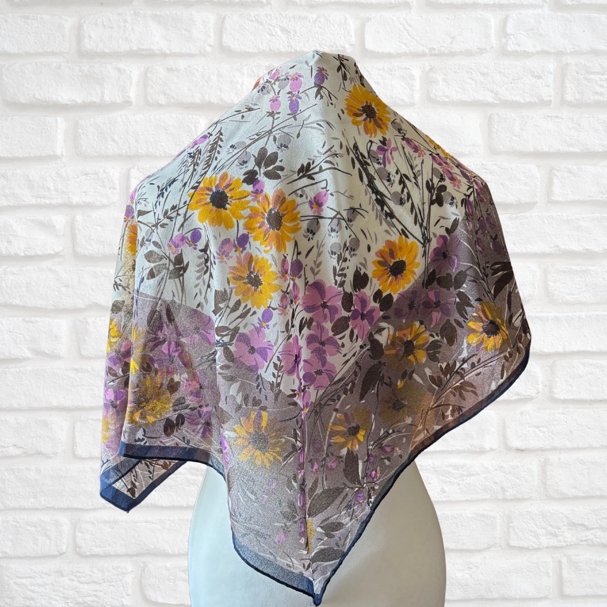 Floral patterned scarf on a mannequin against a white brick wall background