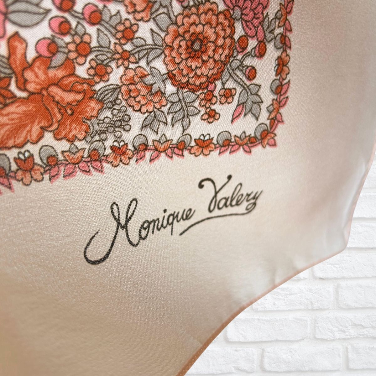 Floral patterned fabric with 'Monique Valery' branding on a white brick background
