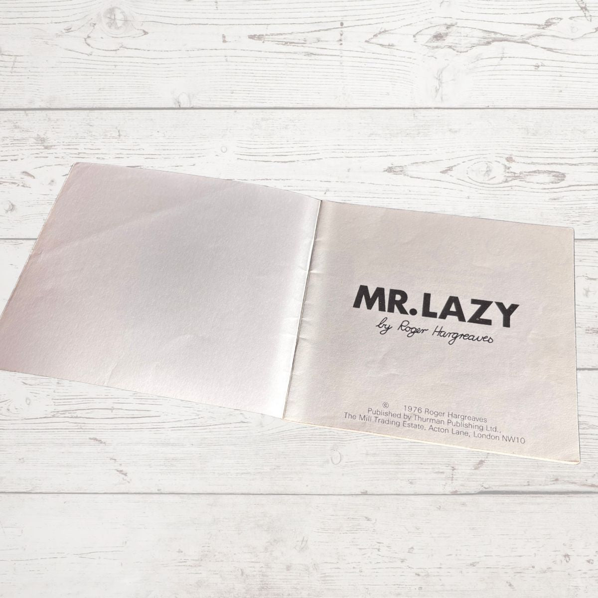 Open book with 'MR. LAZY' title on a light wooden surface
