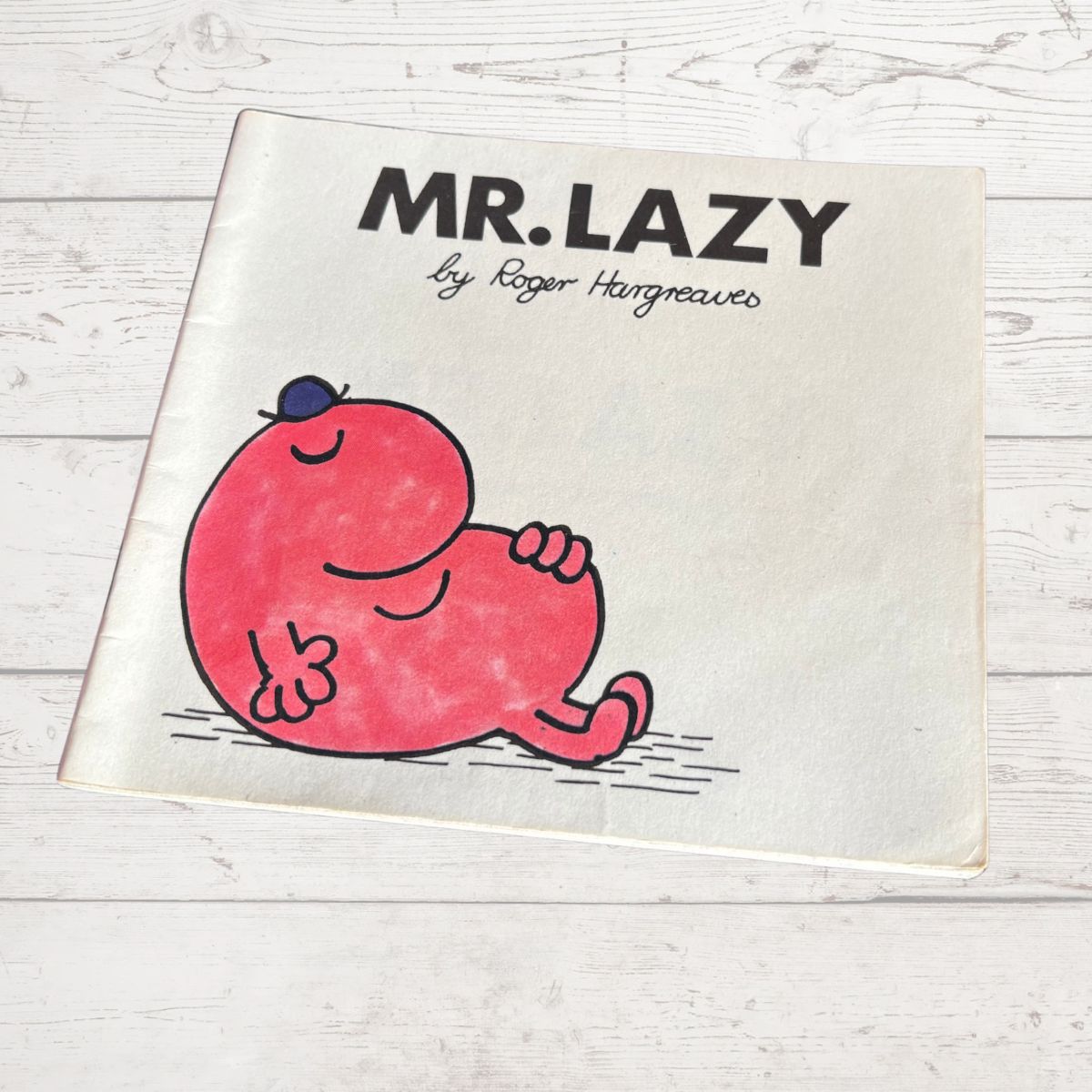 Book titled 'Mr. Lazy' by Roger Hargreaves on a wooden surface