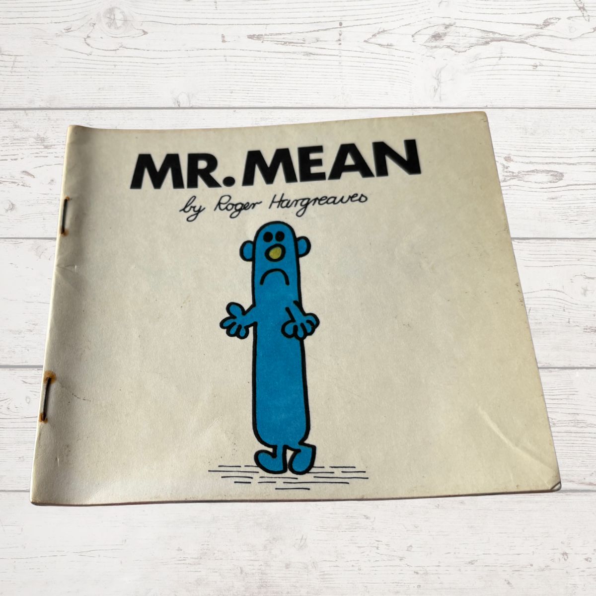 Book titled 'Mr. Mean' by Roger Hargreaves on a wooden surface
