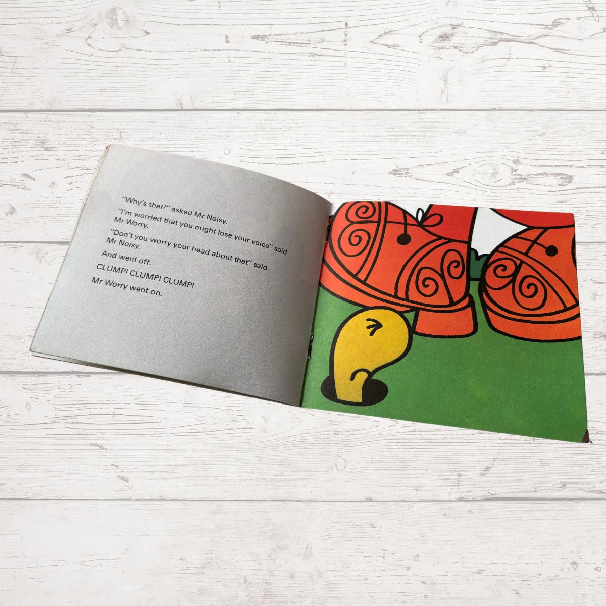 Open book with a cartoon character on a wooden surface