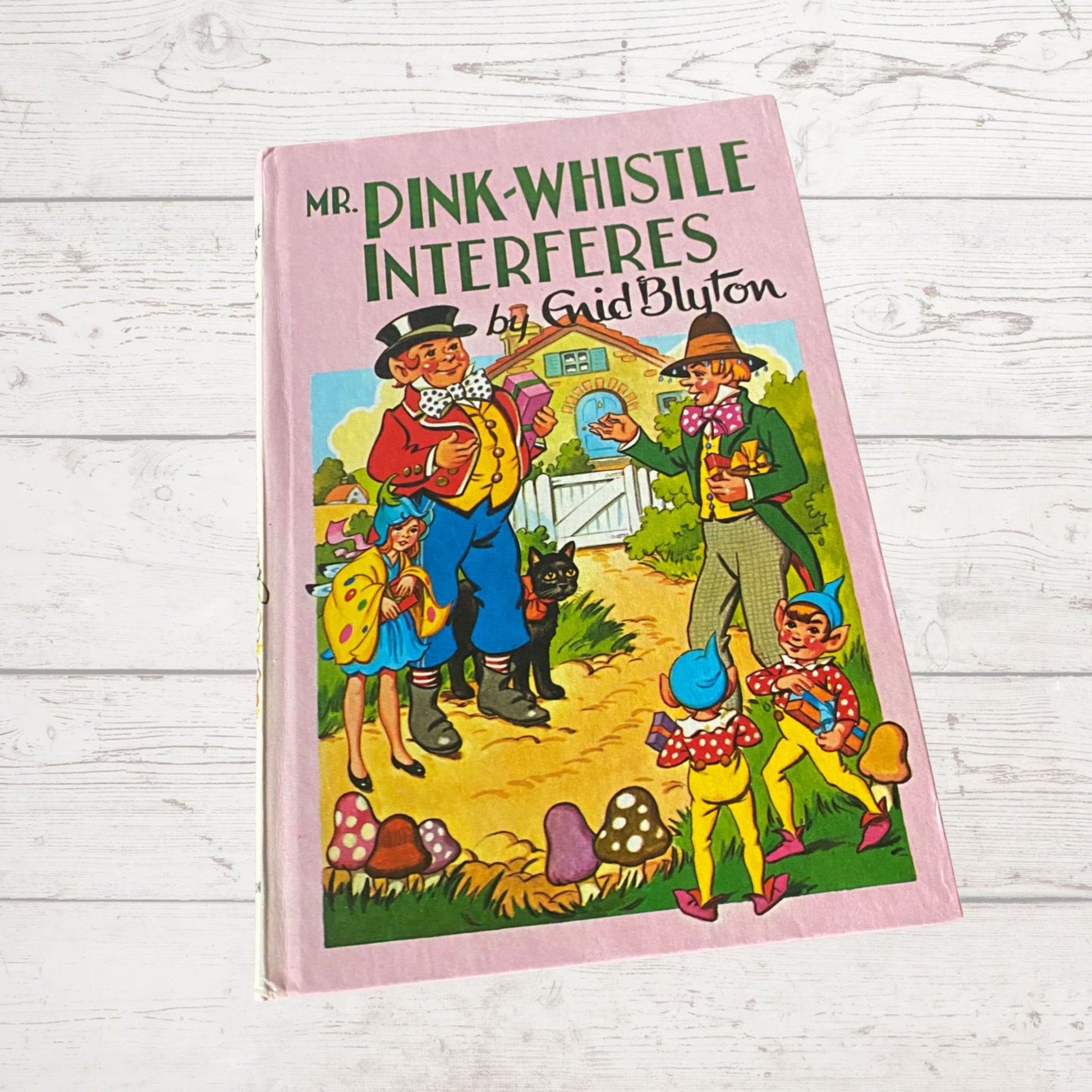 A vintage pink hardback book cover featuring illustrations of characters from 'Mr Pink Whistle Interferes' by Enid Blyton.