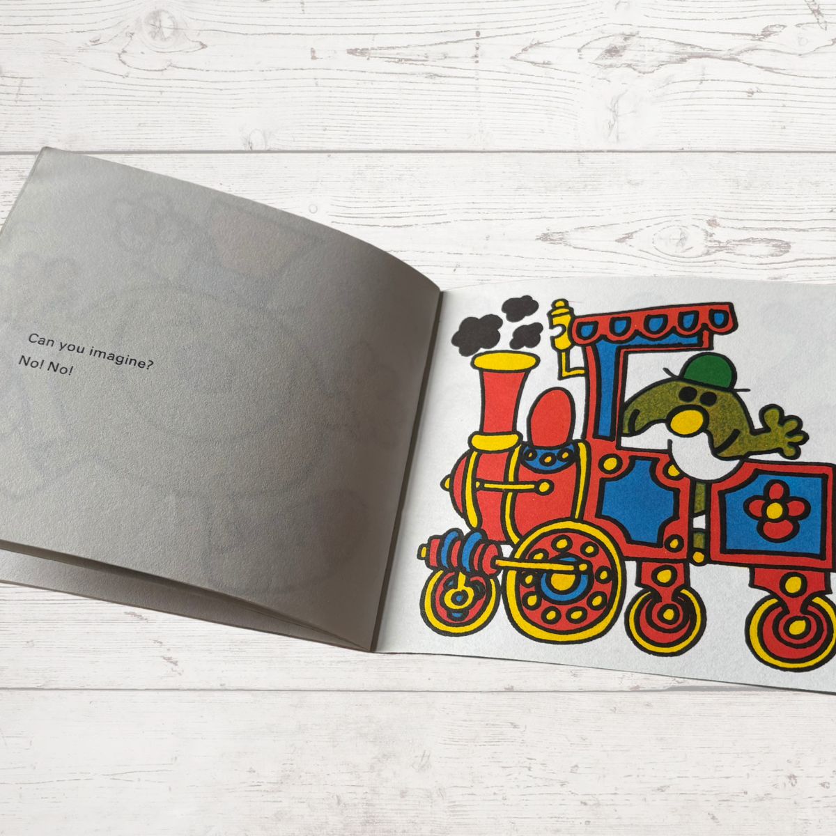 Open book with a colorful train illustration on a wooden surface