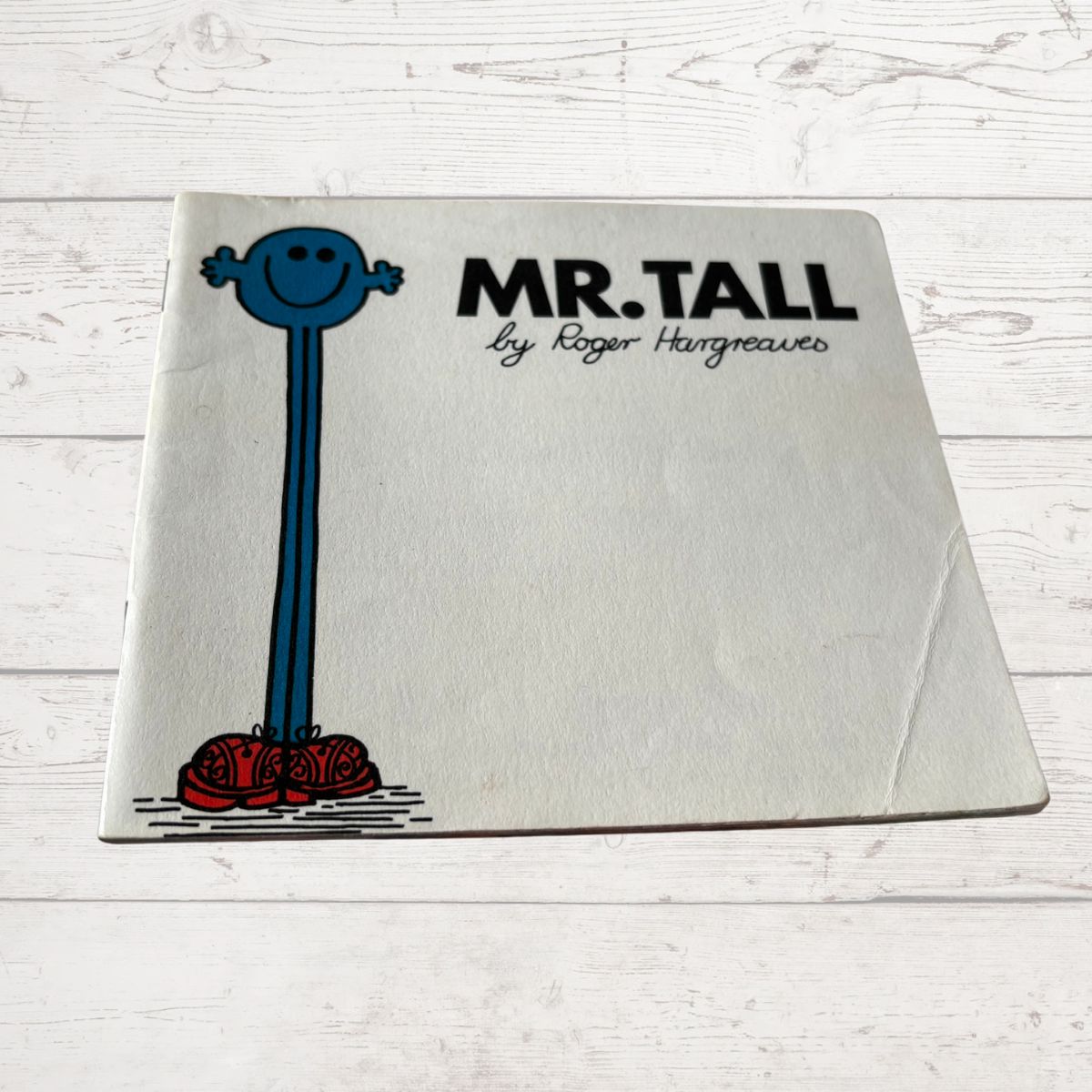 Book titled 'Mr. Tall' by Roger Hargreaves on a wooden surface