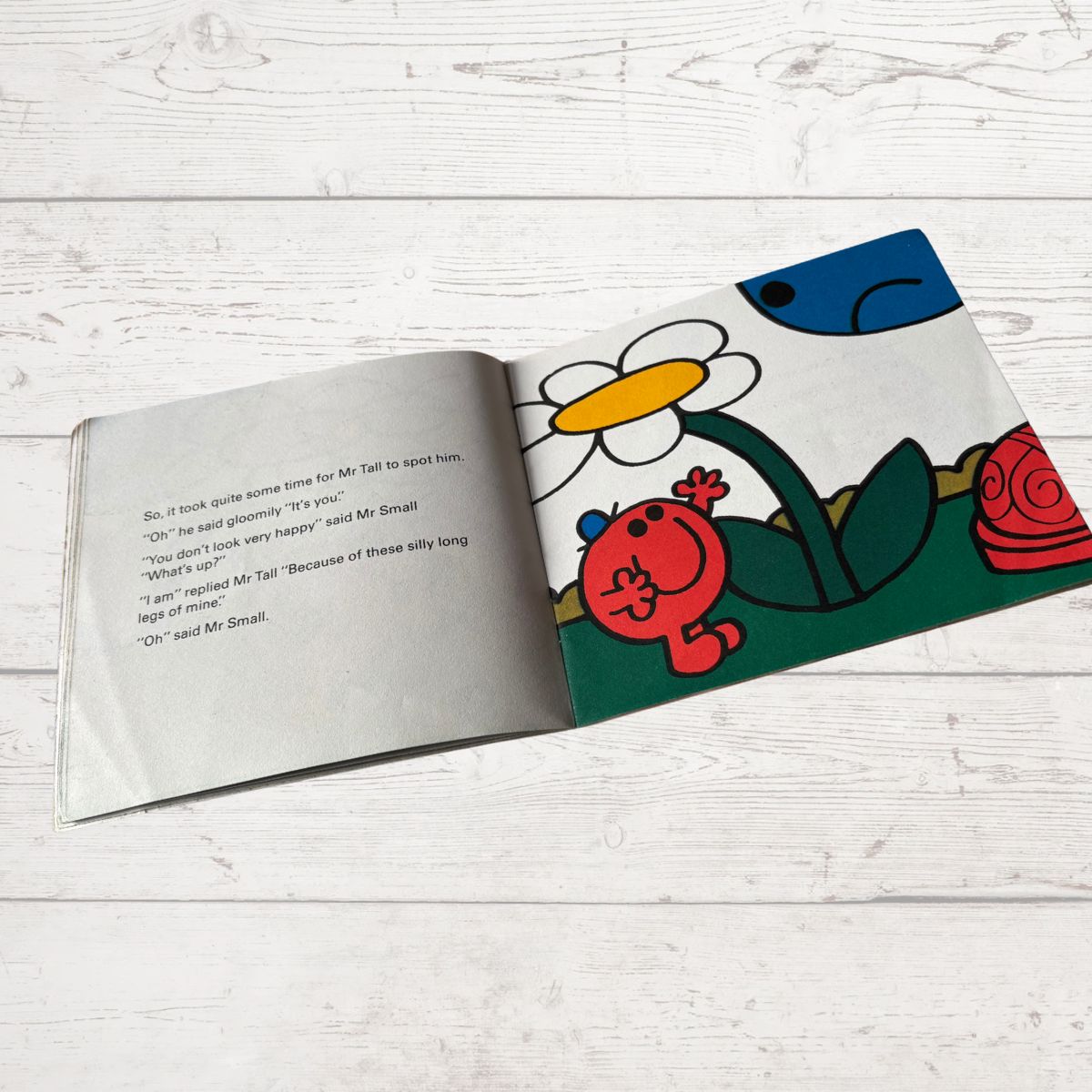 Open book with colorful illustration of a cartoon character on a white wooden surface