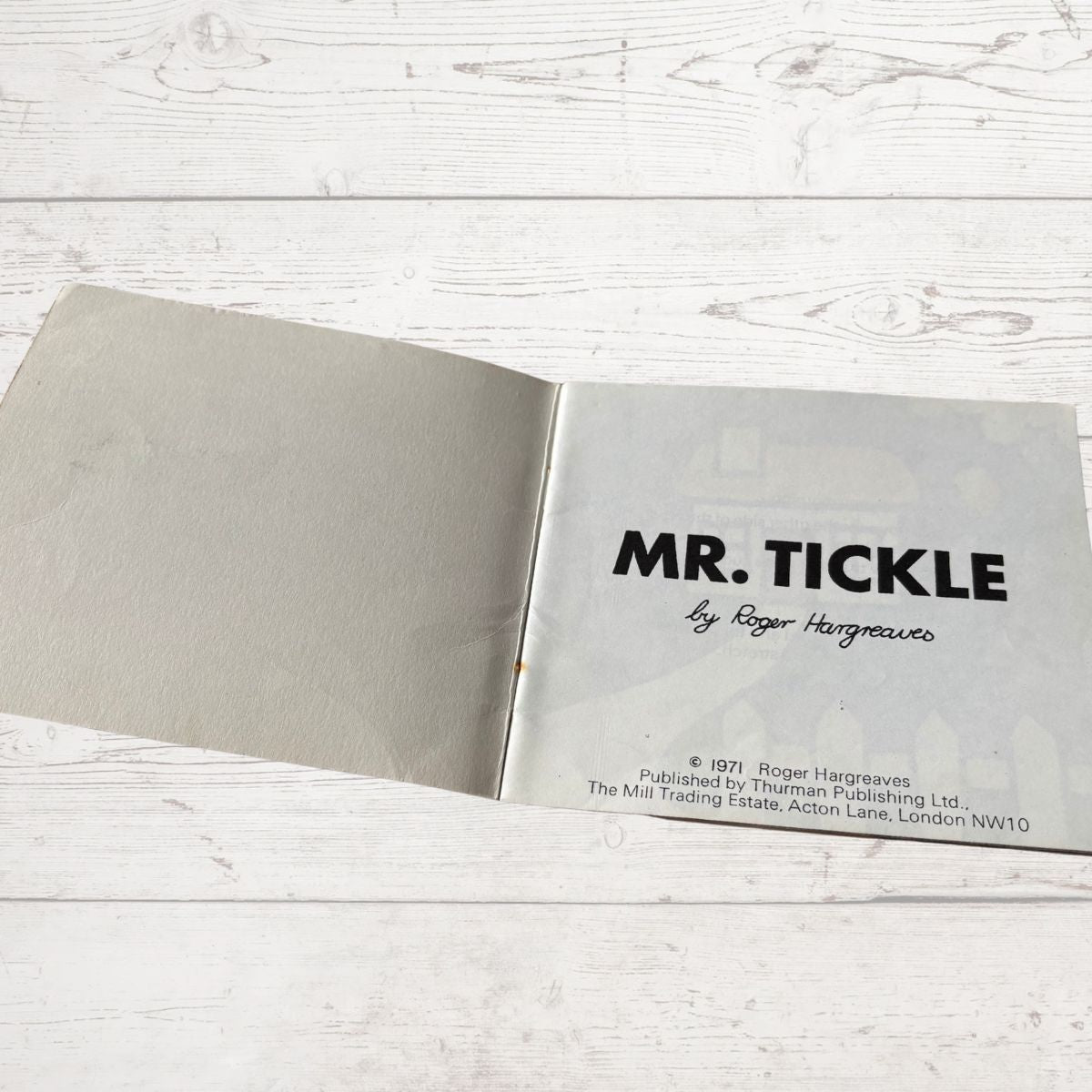 Open book with 'MR. TICKLE' title on a wooden surface