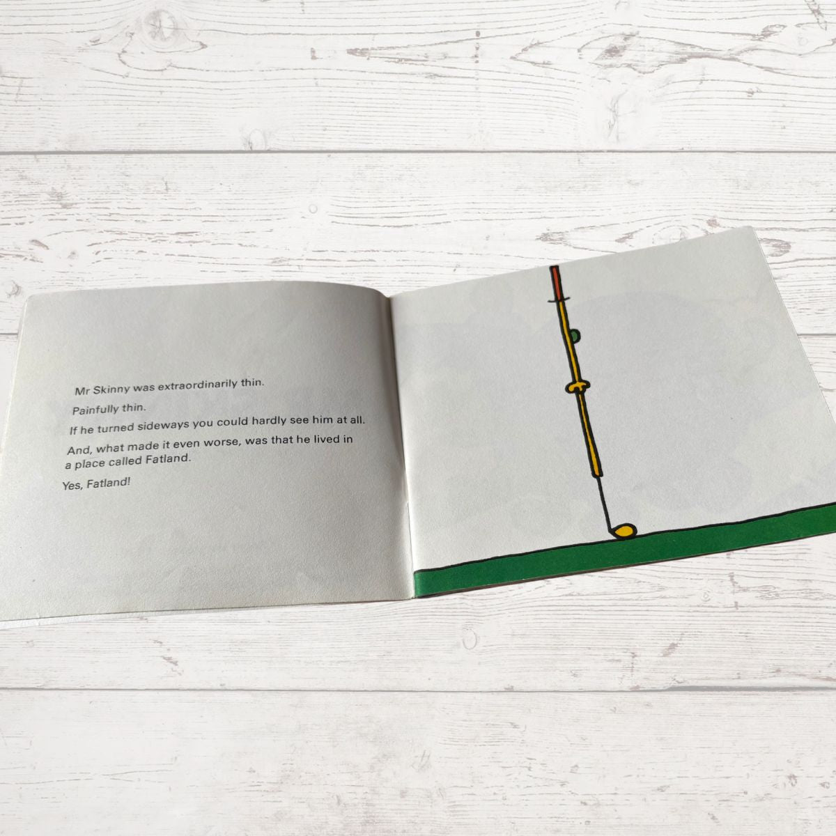 Open book with text and a drawing of a thin stick figure on a wooden surface