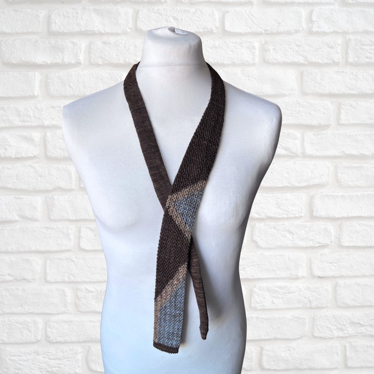 Knitted tie on a mannequin against a white brick wall background