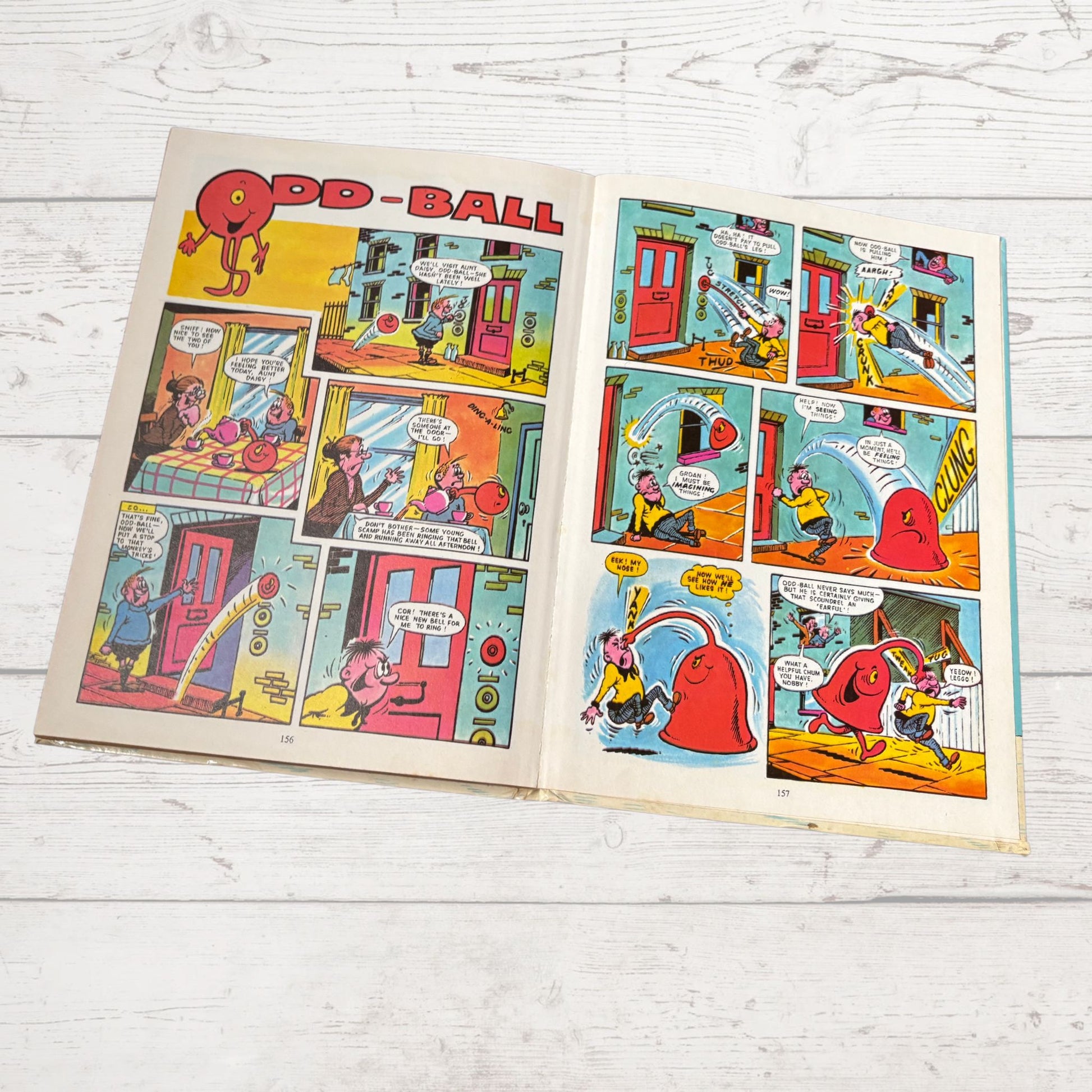 Open comic book with 'Odd-Ball' strip on a wooden surface
