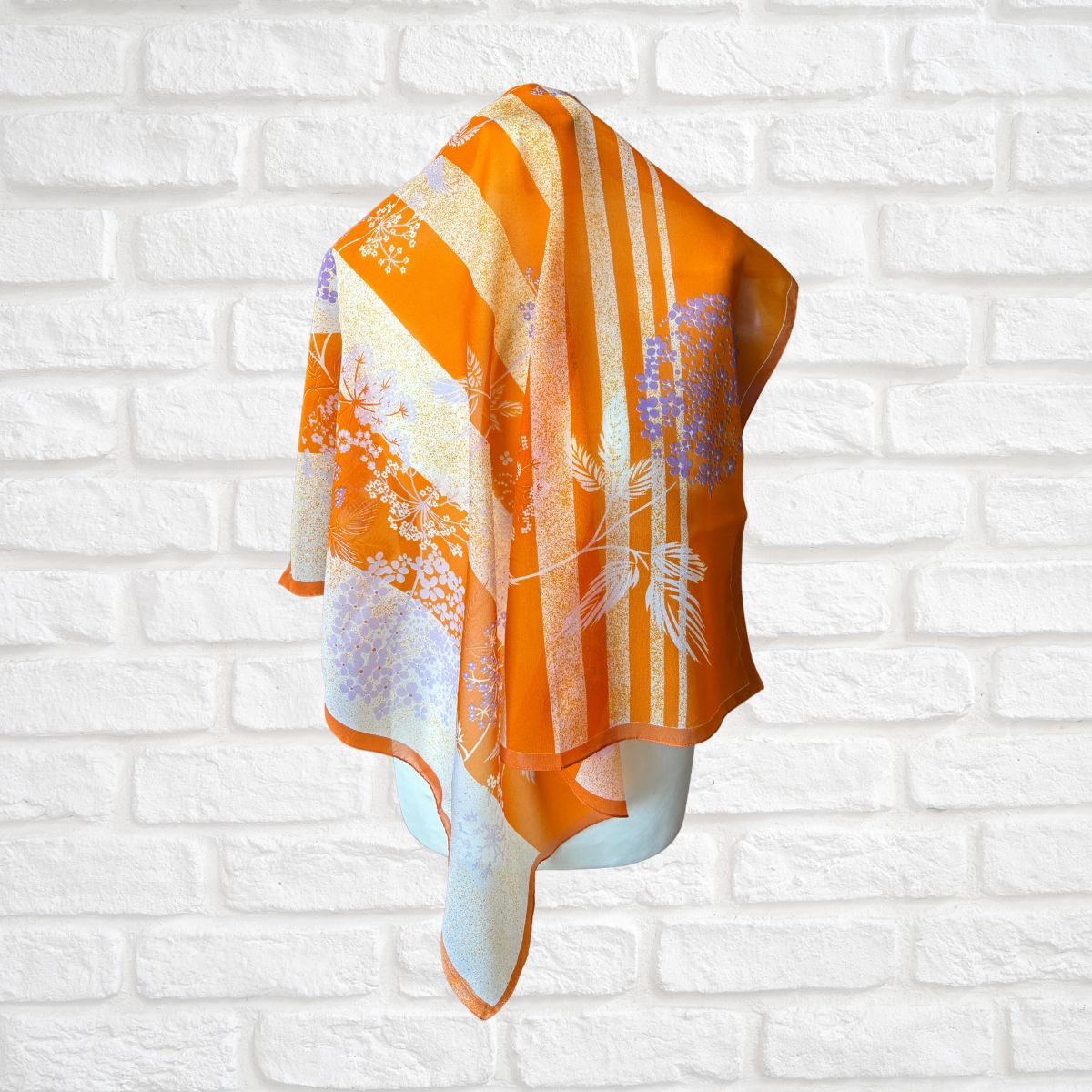 Orange and white patterned towel on a white brick wall background