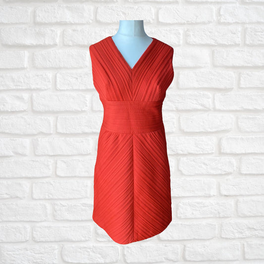 A sleeveless, red textured mini dress with a V-neckline and ribbed bandeau style, displayed on a mannequin against a white brick wall.