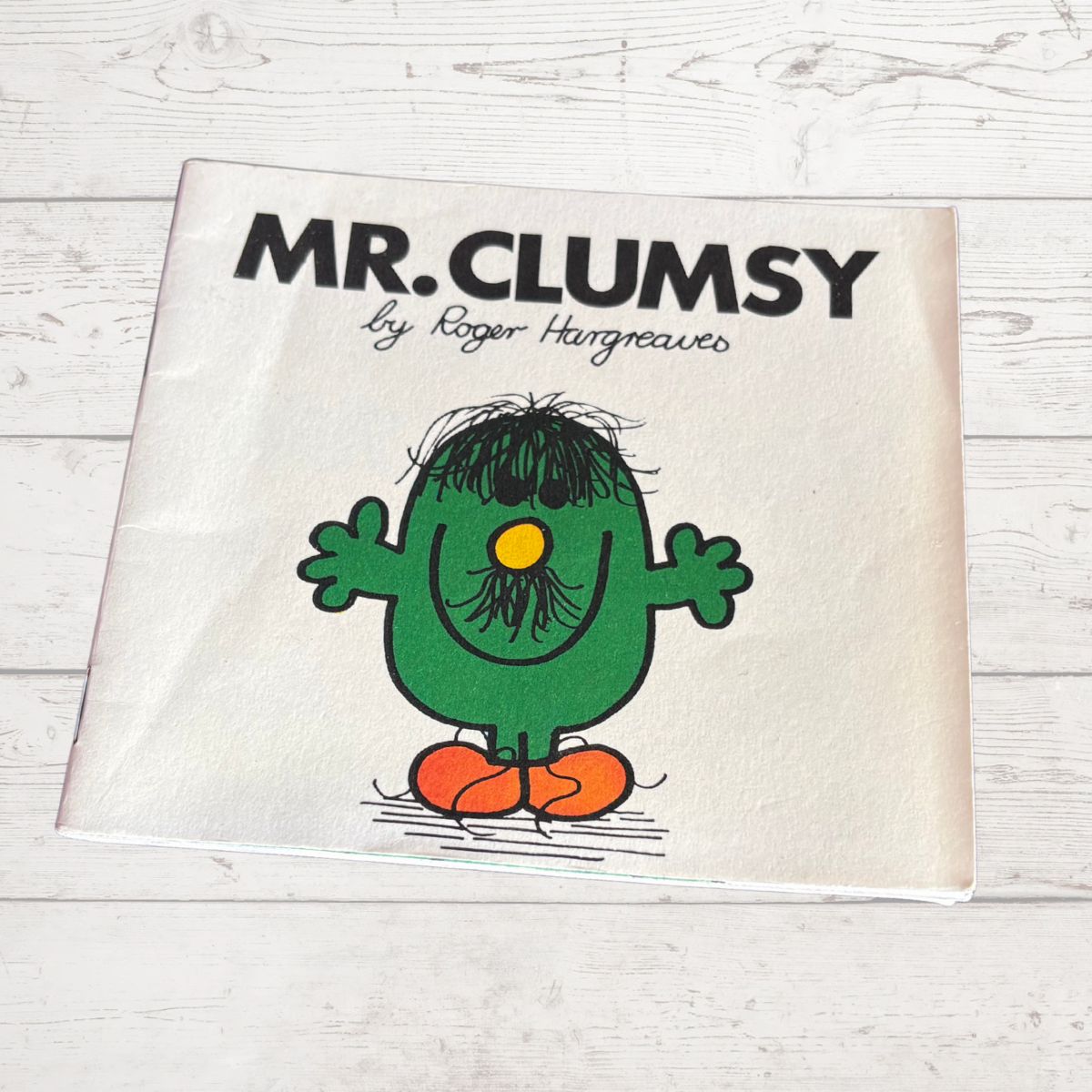 Book cover of 'Mr. Clumsy' by Roger Hargreaves on a wooden surface