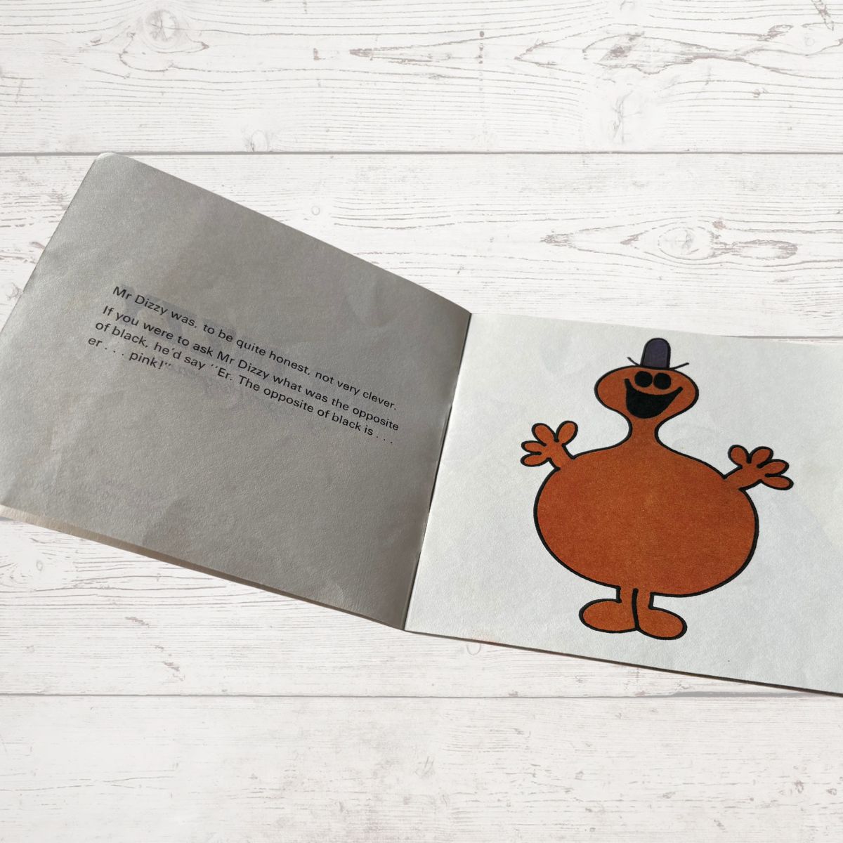 Open book with a cartoon character on a wooden surface