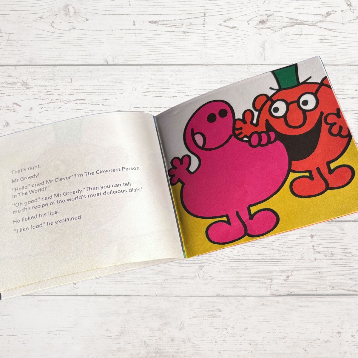 Open book with colorful cartoon characters on a wooden surface