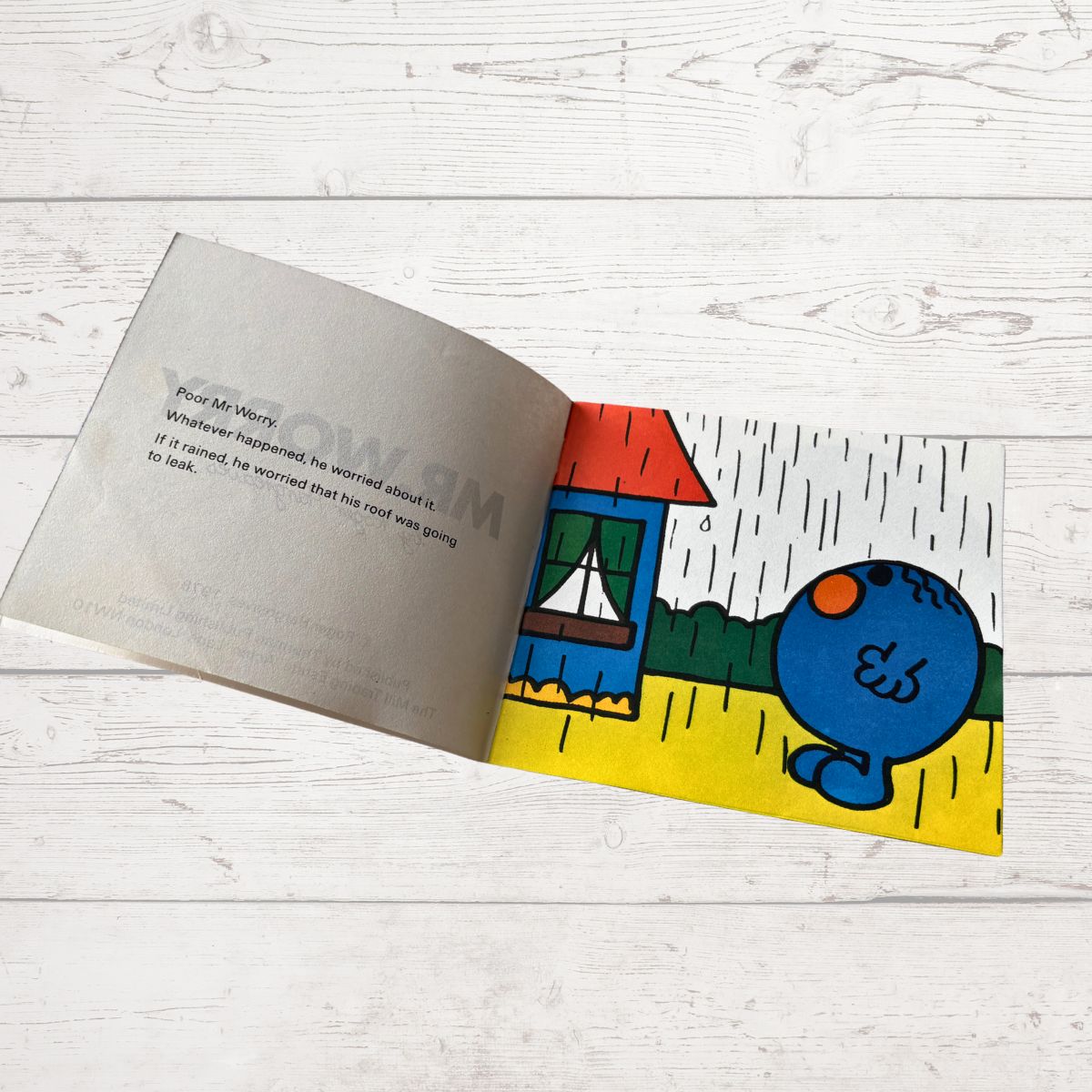 Open book with a colorful illustration of a blue character on a white wooden surface