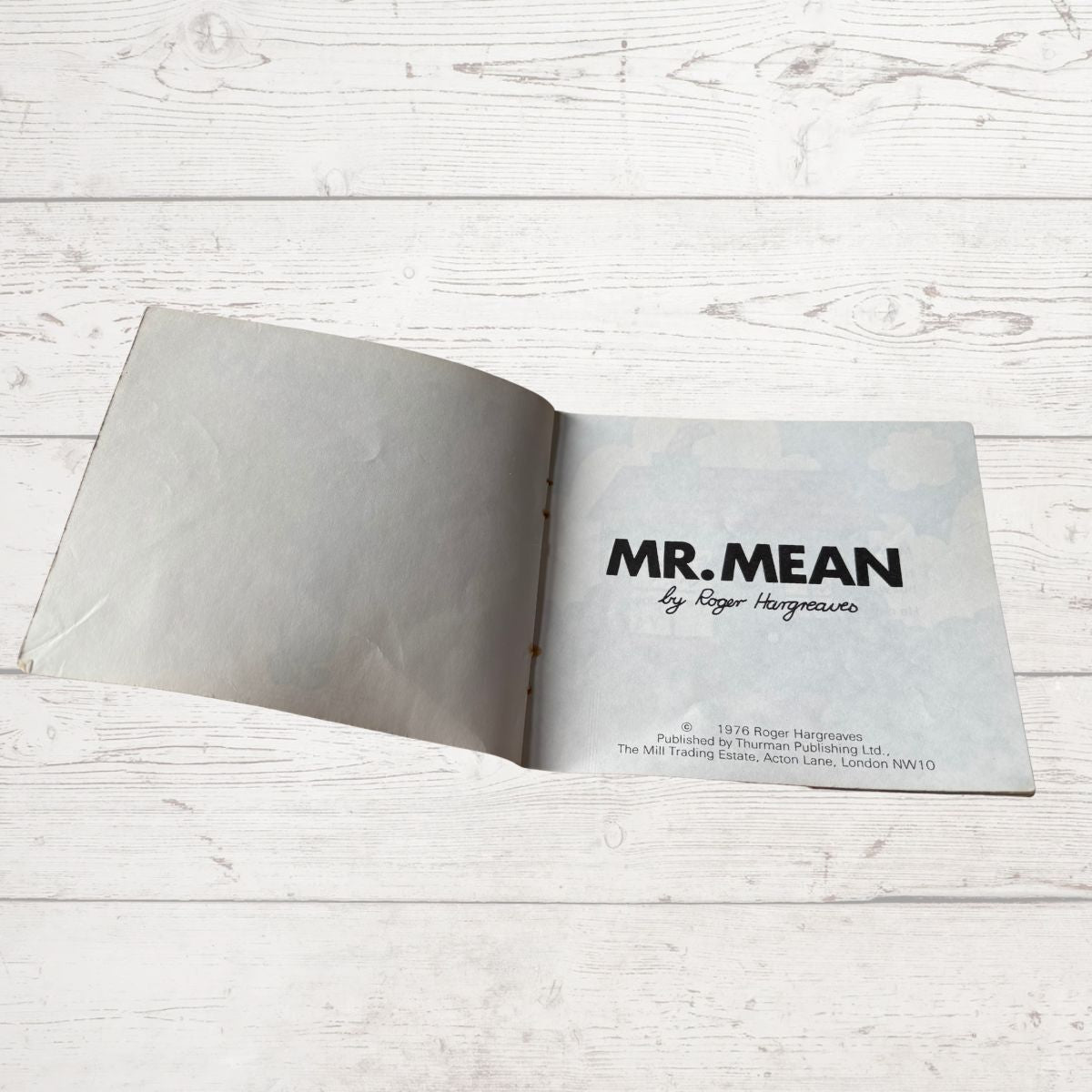 Open book with 'MR. MEAN' title on a light wooden surface