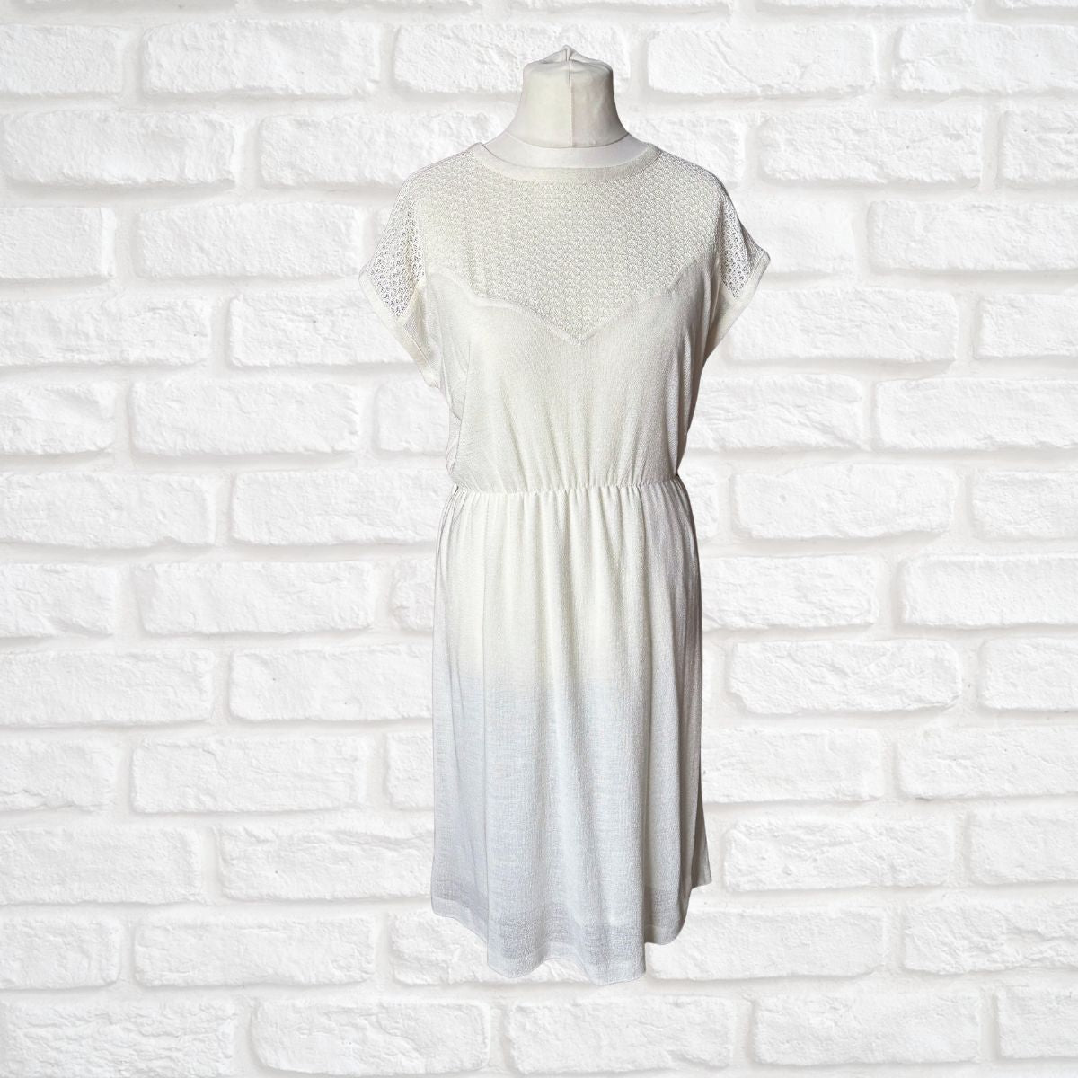 Cream dress on a mannequin against a white brick wall background