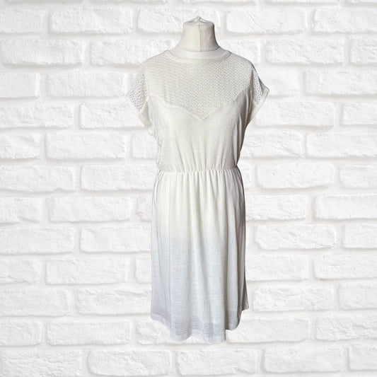 Cream dress on a mannequin against a white brick wall background