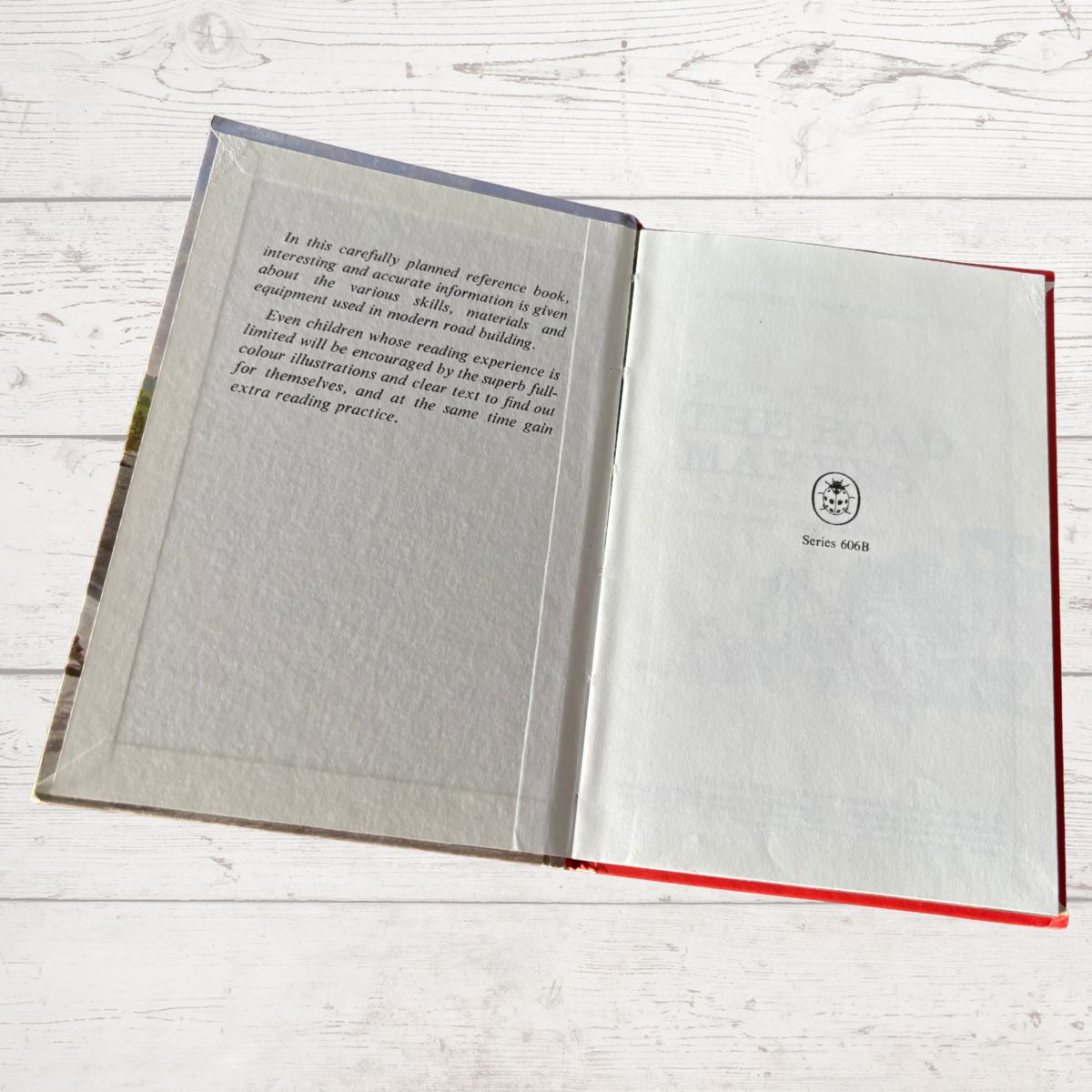 Open book with text and a logo on a light wooden surface