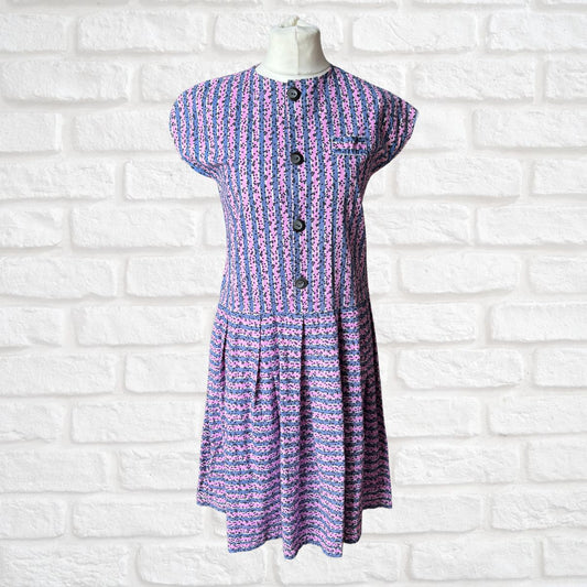 Purple and pink striped dress on a mannequin against a white brick wall background