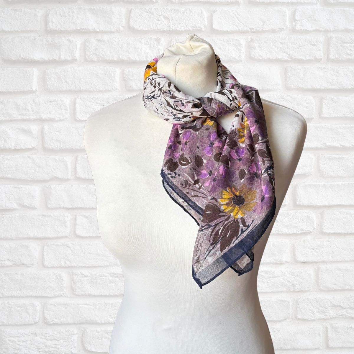 Floral patterned scarf on a mannequin against a white brick wall background