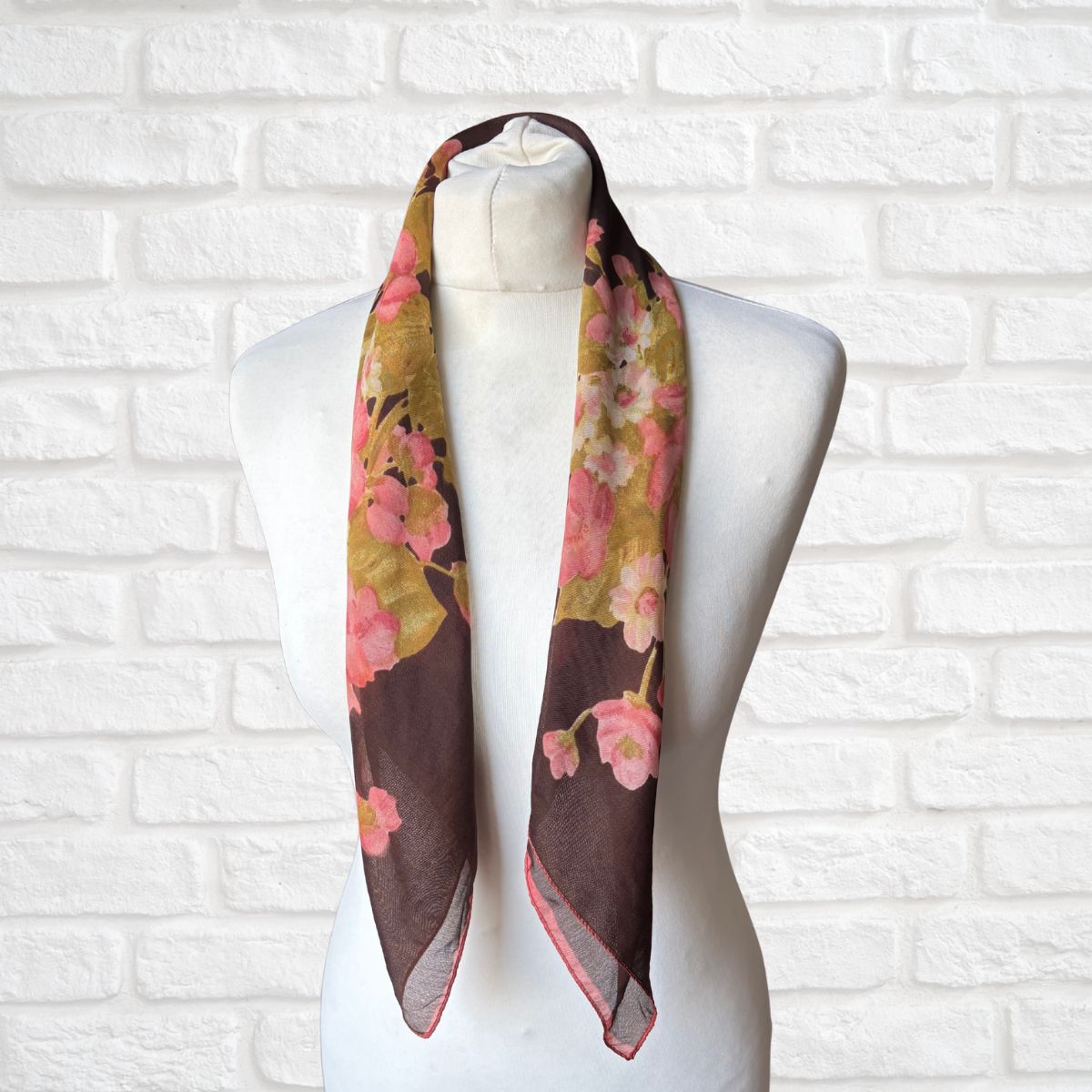Floral scarf on a mannequin against a white brick wall background