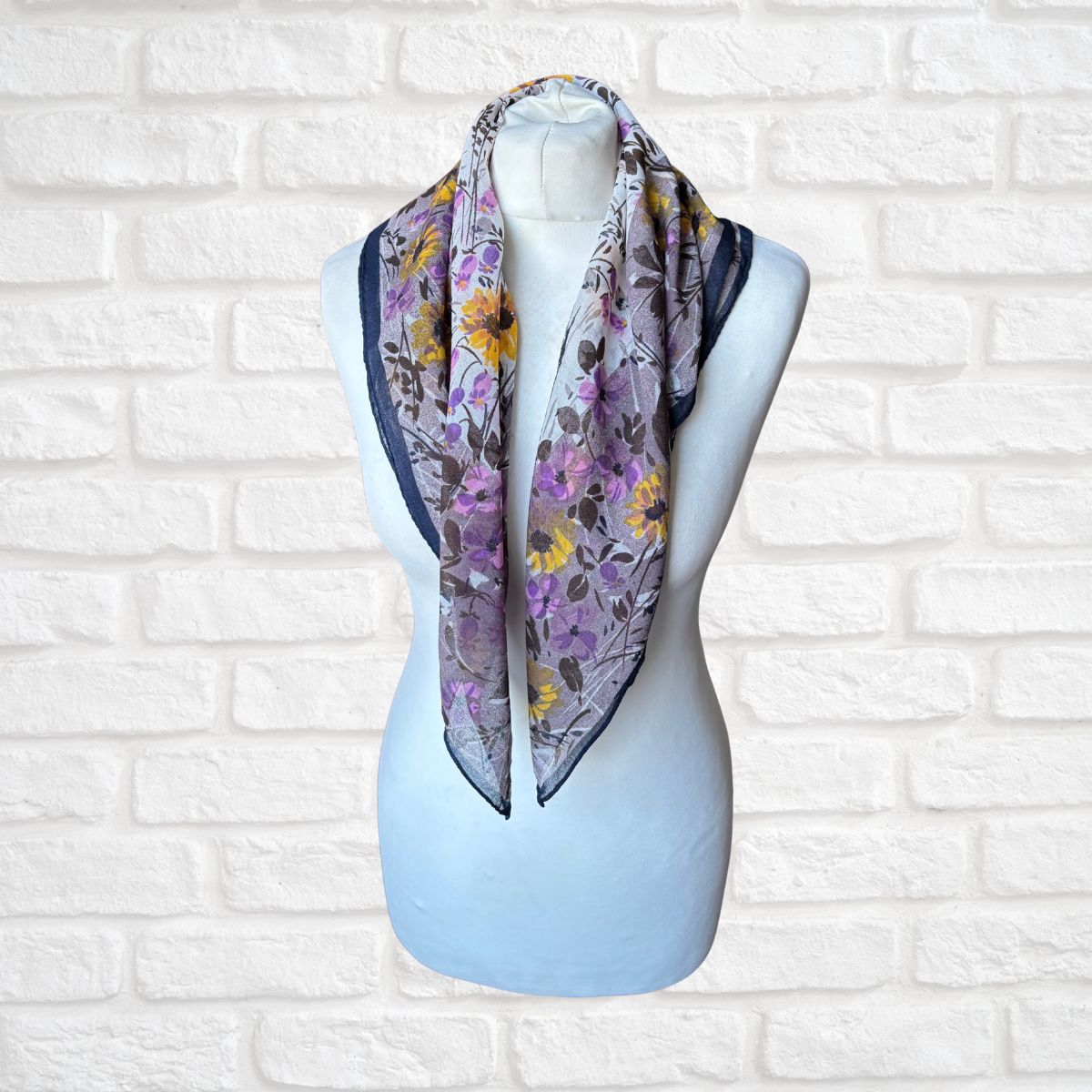 Floral patterned scarf on a mannequin against a white brick wall background