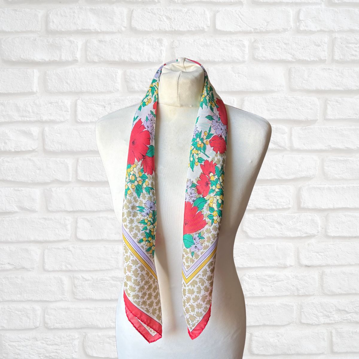 Colorful floral scarf on a mannequin against a white brick wall