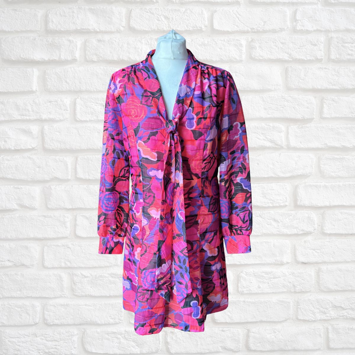 Floral patterned dress on a mannequin against a white brick wall background