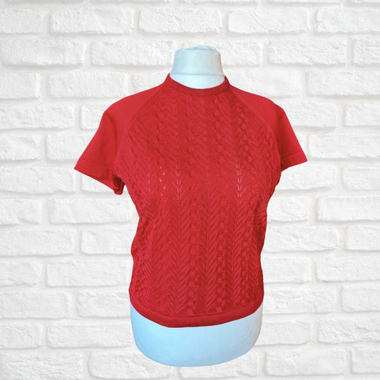 Red knitted sweater on a mannequin against a white brick wall background