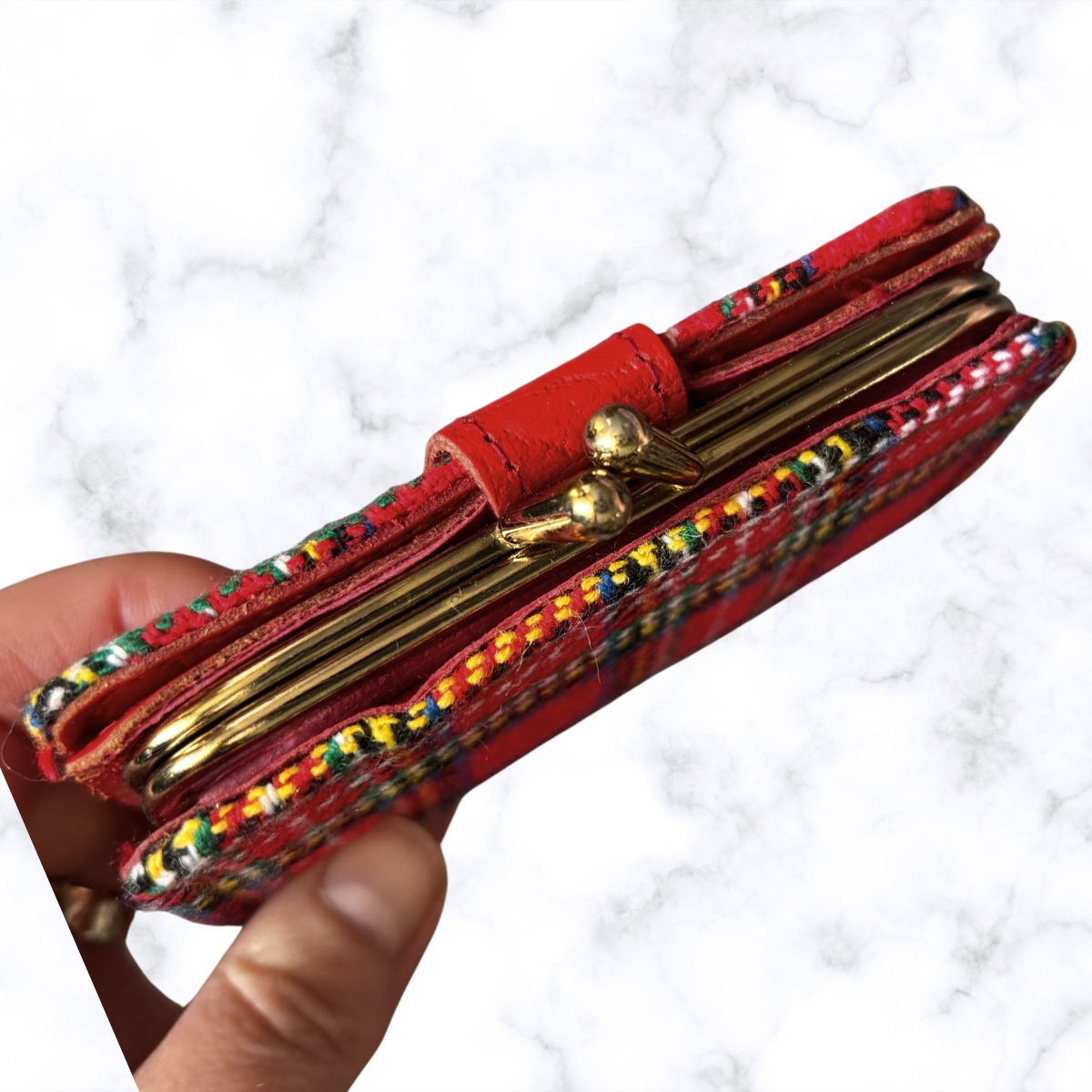 Red wallet with colorful accents held by a hand on a white background