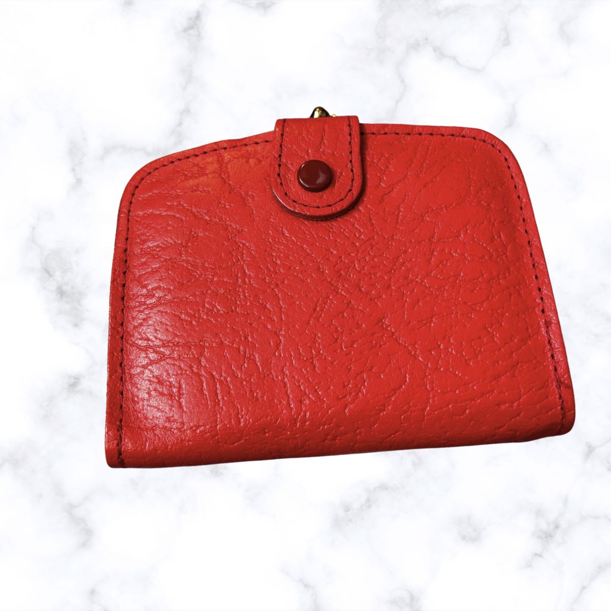 Red leather wallet on a white marble background