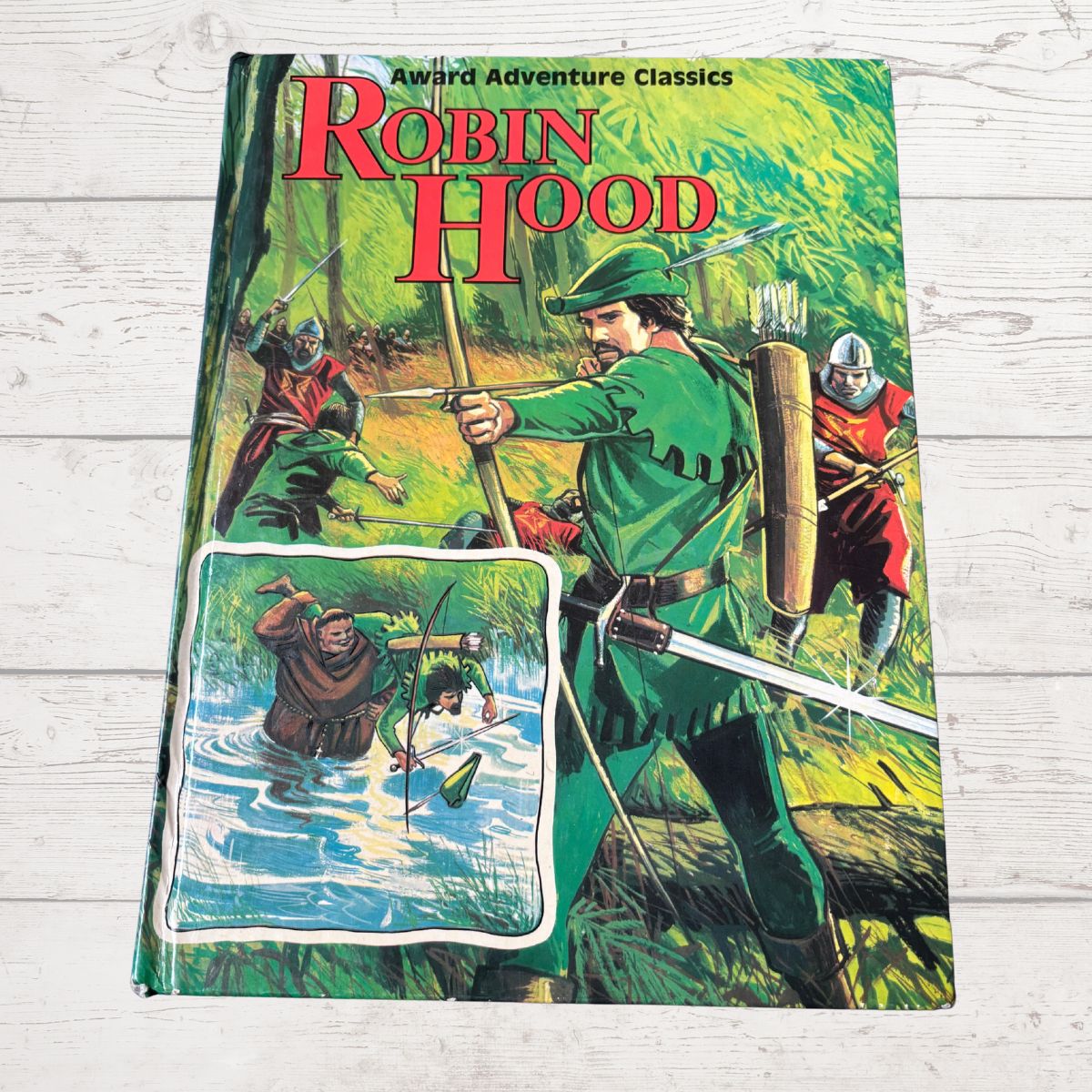Book cover of 'Robin Hood' with illustrations of Robin Hood and his companions on a wooden surface.