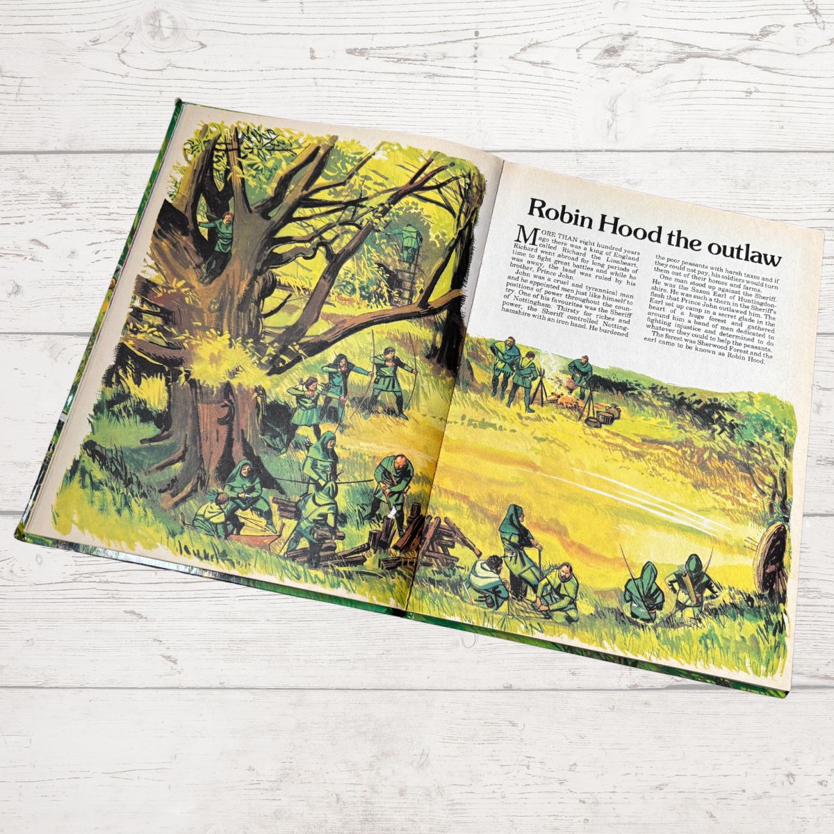 Open book with illustrations of Robin Hood and text on a wooden surface