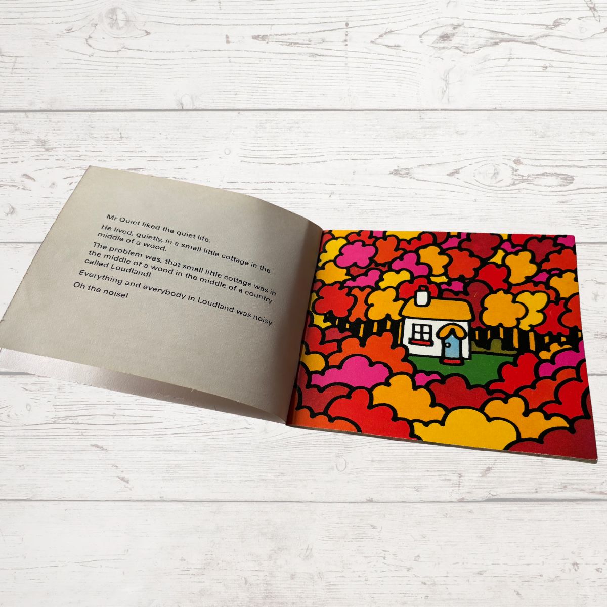 Open book with colorful illustration of a house on a white wooden surface
