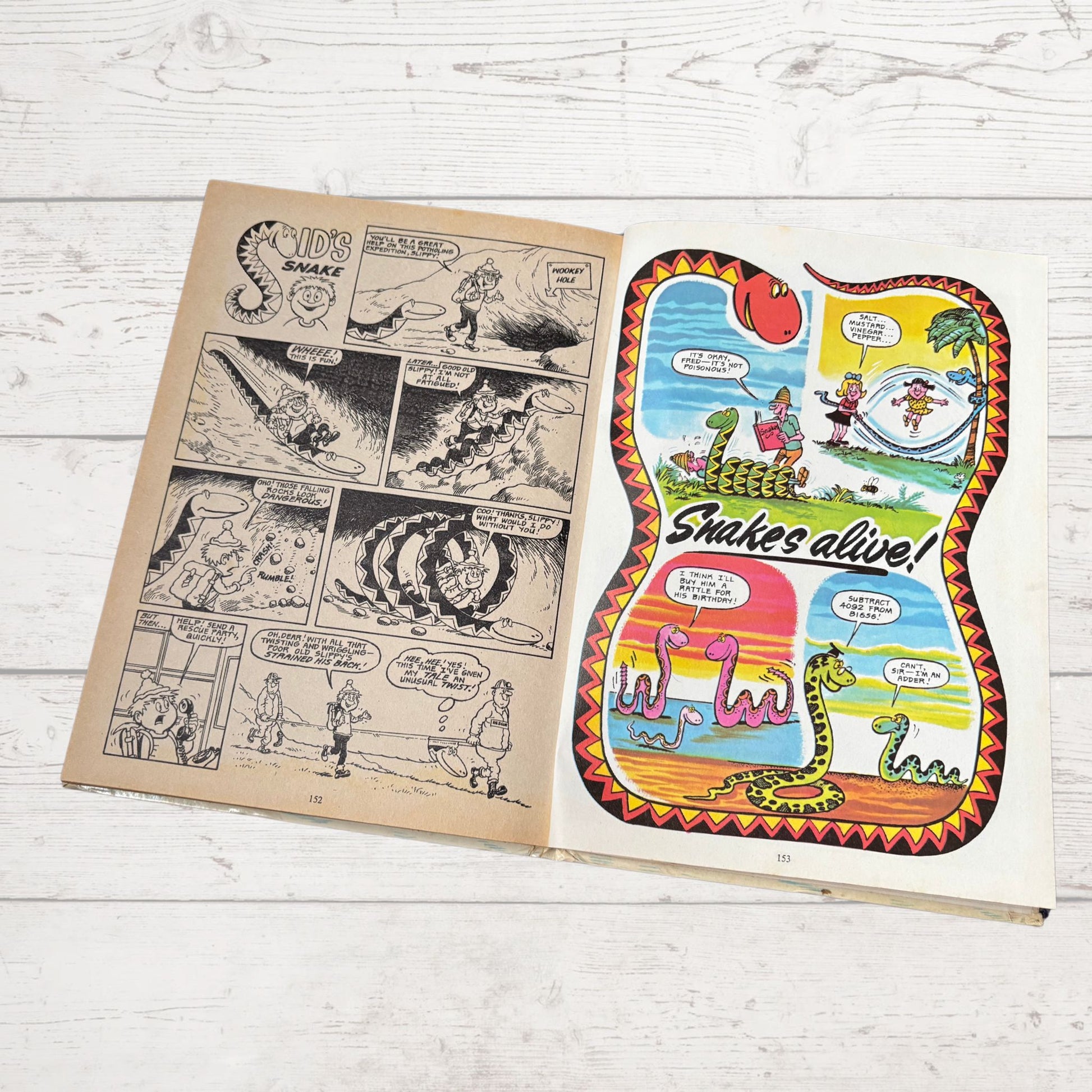 Open comic book with snake-themed illustration on a wooden surface