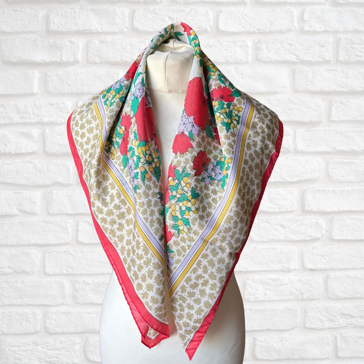 Colorful floral patterned scarf on a mannequin against a white brick wall background