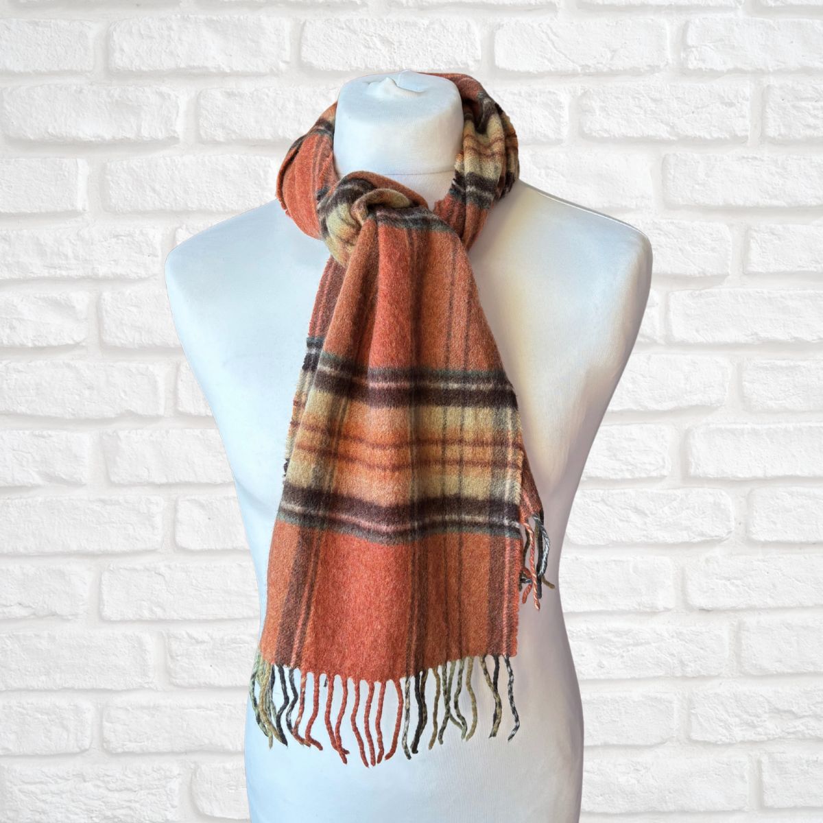 Plaid scarf on a mannequin against a white brick wall
