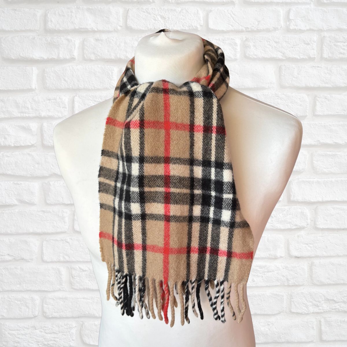 Plaid scarf on a mannequin against a white brick wall background