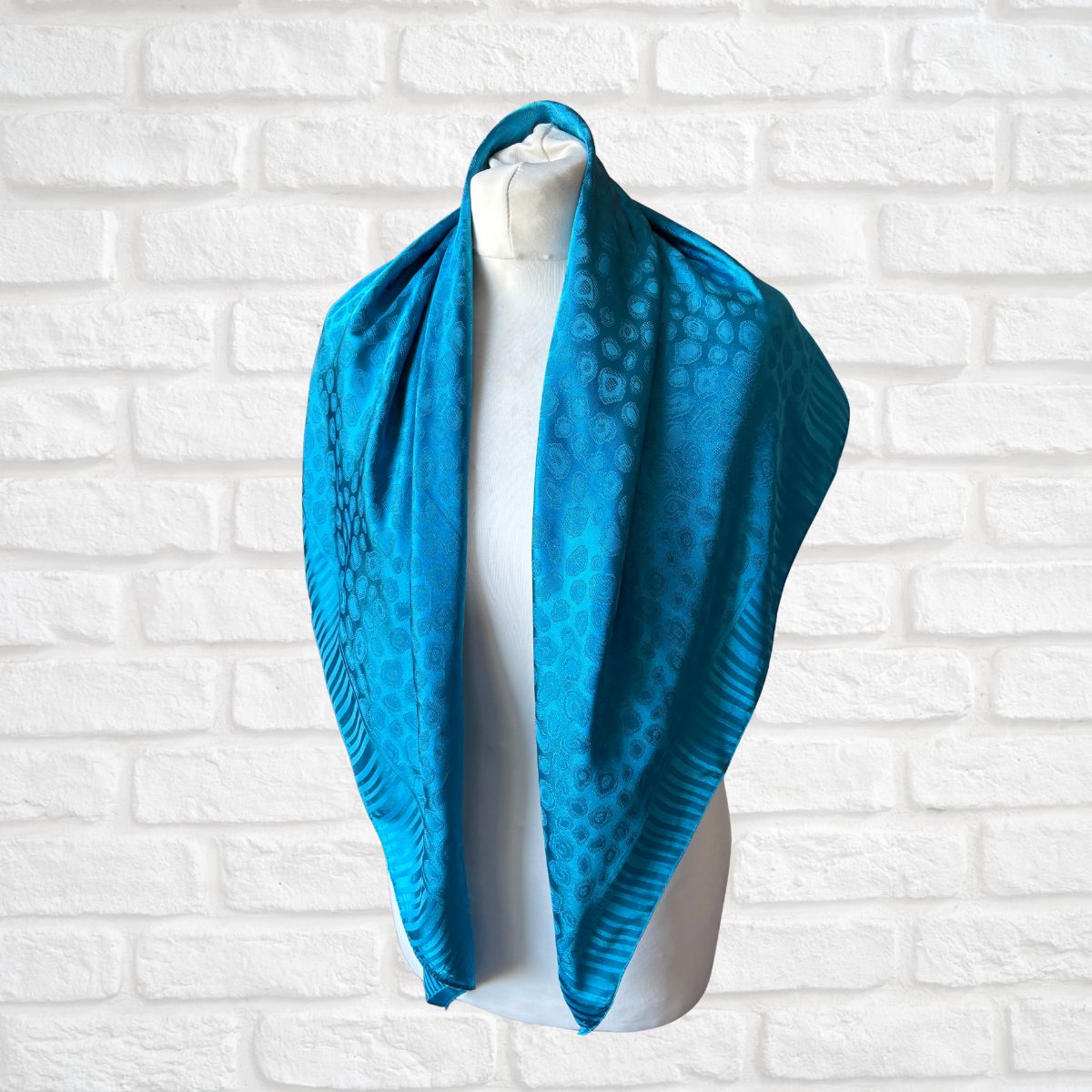 Blue scarf on a mannequin against a white brick wall
